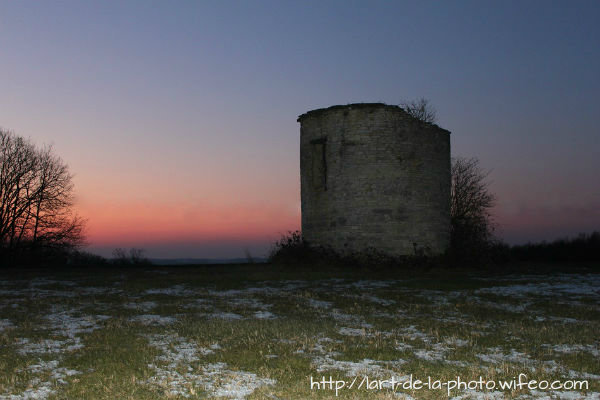 photographie d`un moulin a vent sous un couché de soleil